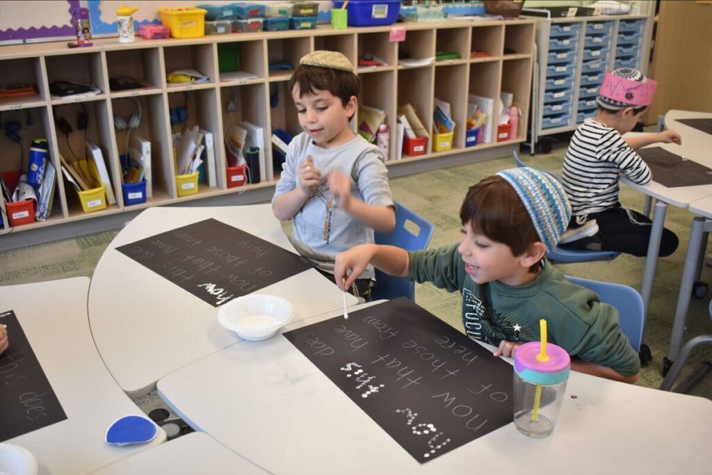 Hillel Torah kindergarten students creatively practicing word recognition through hands-on literacy activities.